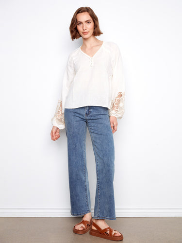 Elegant white top showcasing braided V-neck design paired with delicate embroidered details by Charlie B.