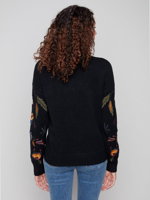 Stylish black sweater highlighted by embroidered flowers and comfortable ribbed cuffs, ideal for any occasion by Charlie B.