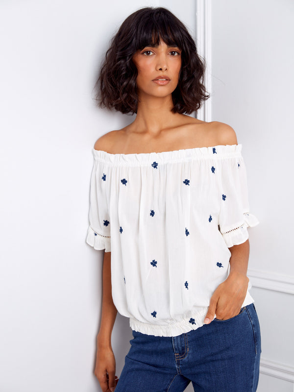 Fashionable white blouse detailed with blue floral embroidery, designed with short flutter sleeves by Charlie B.