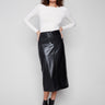 Black faux leather midi skirt with convenient side pockets, paired elegantly with a white top and black ankle boots by Charlie B.