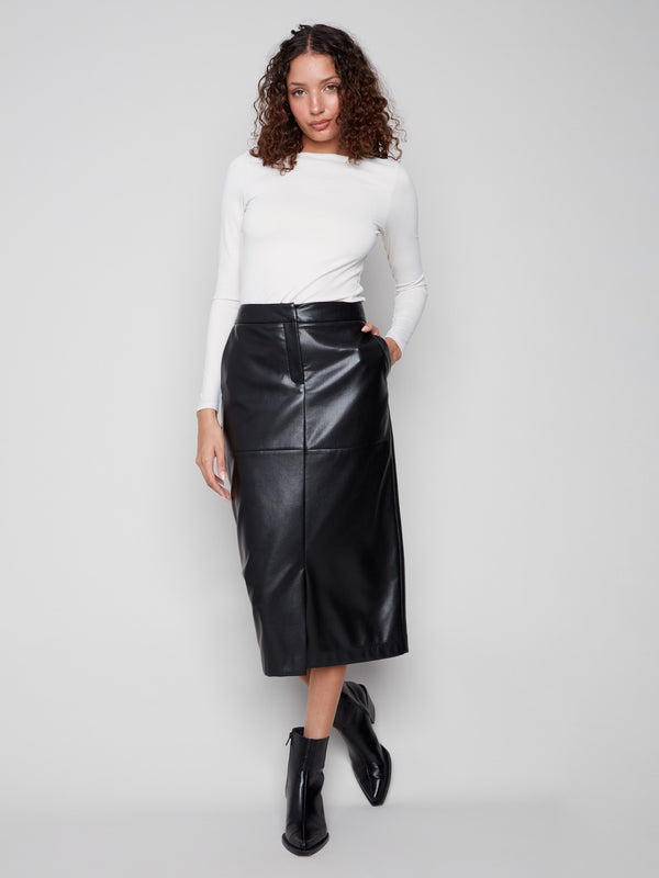 Chic black faux leather midi skirt featuring a stylish slit front hem, complemented by a white top and ankle boots by Charlie B.