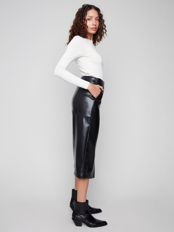 Sophisticated black faux leather midi skirt with lined fabric, styled with a classic white top and sleek black ankle boots by Charlie B.