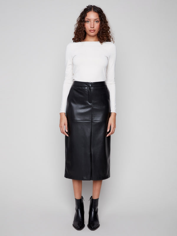 Trendy black faux leather midi skirt showcasing its elegant midi length, matched perfectly with a white top and ankle boots by Charlie B.