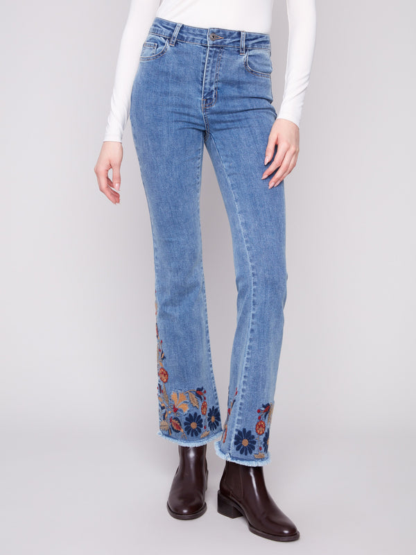 These medium blue jeans boast a regular rise and five-pocket design, adorned with vibrant floral embroidery by Charlie B.