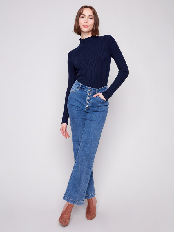 Medium blue jeans showcasing embellished buttons closure, perfectly matched with a dark top by Charlie B.