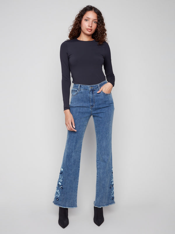 These medium blue jeans feature a stunning flare leg with floral embroidery, perfect for adding flair to any outfit by Charlie B.