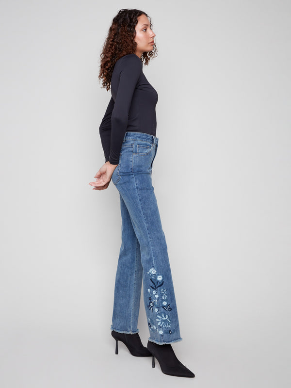 Long length denim jeans in medium blue, adorned with intricate floral embroidery along the sides for a chic look by Charlie B.