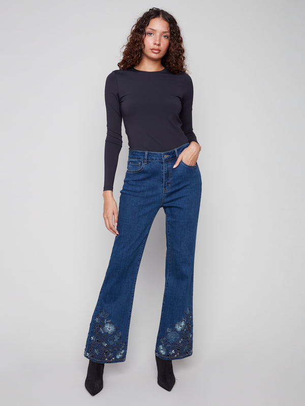 Indigo jeans with a flare fit and intricate floral lace at the hem, crafted from stretch denim for comfort by Charlie B.
