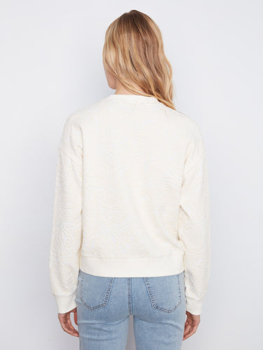 Stylish buttercream crew neck sweatshirt offering a relaxed fit and detailed floral soutache design on soft fabric by Charlie B.