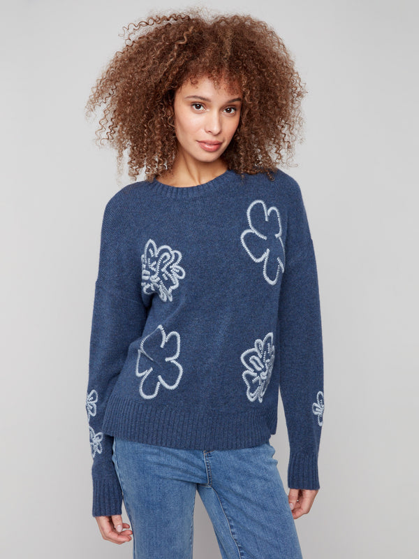 Denim sweater with a crew neck, showcasing a charming embroidered floral design, complemented by ribbed cuffs. By Charlie B.