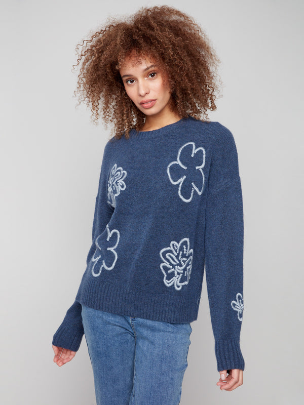 Elegant denim sweater adorned with an embroidered floral pattern and ribbed cuffs for added style. By Charlie B.