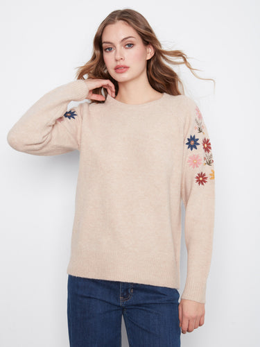 A charming sweater with raglan sleeves that provide a relaxed fit, complemented by delicate floral details for added elegance by Charlie B.