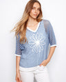 Blue knit top with a V-neck design and floral appliqué, perfect for a relaxed fit. Styled by Charlie B.