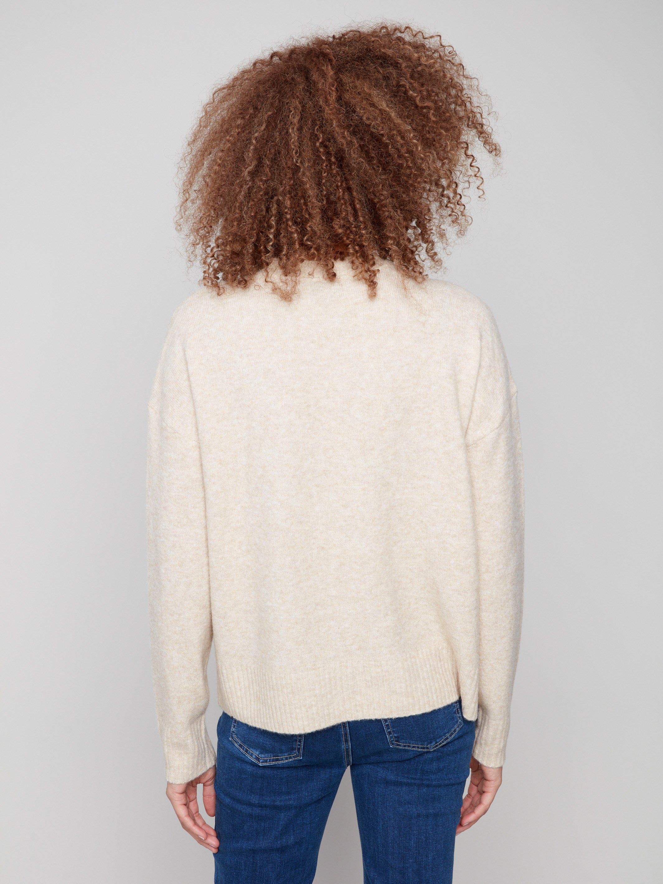 Stylish beige sweater showcasing drop shoulders and a unique floral jacquard motif by Charlie B.