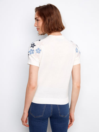 A chic white knit top showcasing a classic crew neckline and beautifully embroidered floral designs on the shoulders by Charlie B.