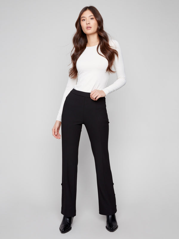 Black flare pants featuring long length, paired with a white top, by Charlie B.