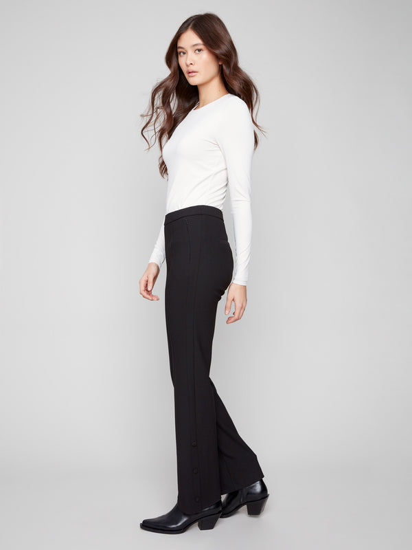 Elegant black flare pants with snap buttons at hem slits and a white top, by Charlie B.