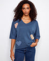 Blue sweater with a V-neckline featuring heart patterns, crafted for a relaxed fit. The elbow sleeves add a casual touch. By Charlie B.