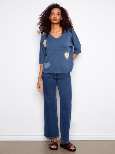 This charming blue sweater displays an elegant V-neck and is designed with lurex thread for subtle sparkle, enhancing its appeal. By Charlie B.