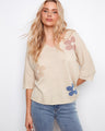 The sweater features a relaxed fit with charming floral accents, perfect for casual outings. Crafted with attention to detail by Charlie B.