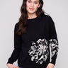Black sweater showcasing a relaxed fit with intricate jacquard floral design, perfect for stylish comfort by Charlie B.