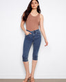 Model in medium blue capri jeans featuring a sleek slim fit and knee length. Crafted with stretch denim for comfort by Charlie B.