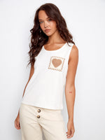 Ecru knit tank top featuring a sleeveless design and crochet heart pocket detail by Charlie B.
