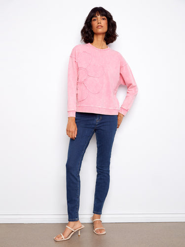 Stylish pink top with drop shoulders and a delightful flower applique detail, adding flair to your wardrobe essentials. By Charlie B.