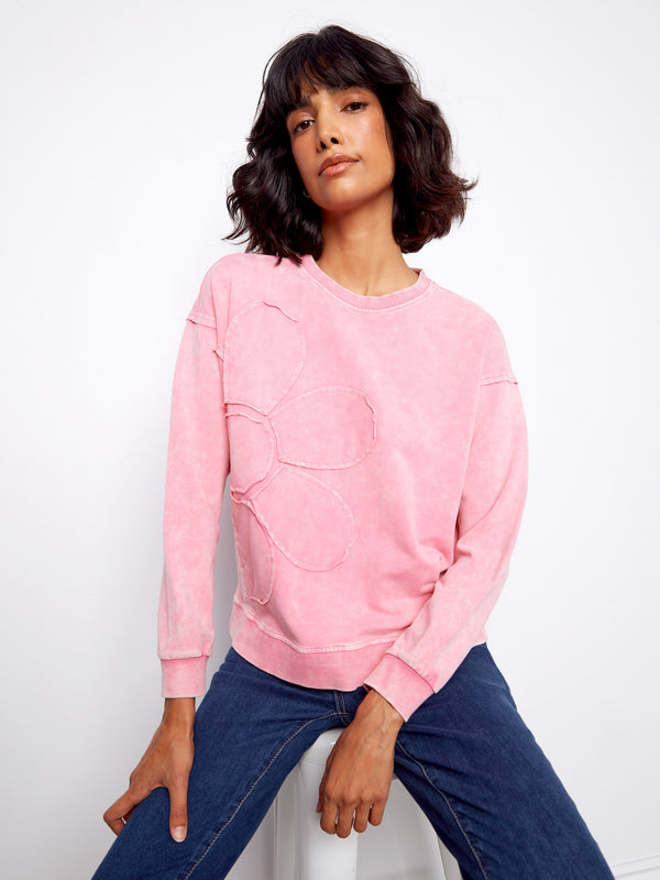 Chic pink pullover adorned with ribbed neck, hem, and cuffs complemented by an eye-catching flower applique design. By Charlie B.