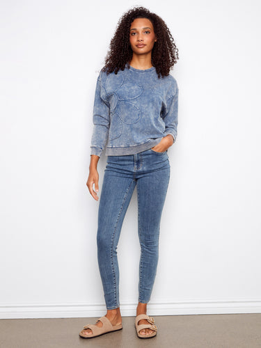 Adorned with a flower applique design, this blue top adds a touch of whimsy to your wardrobe by Charlie B.