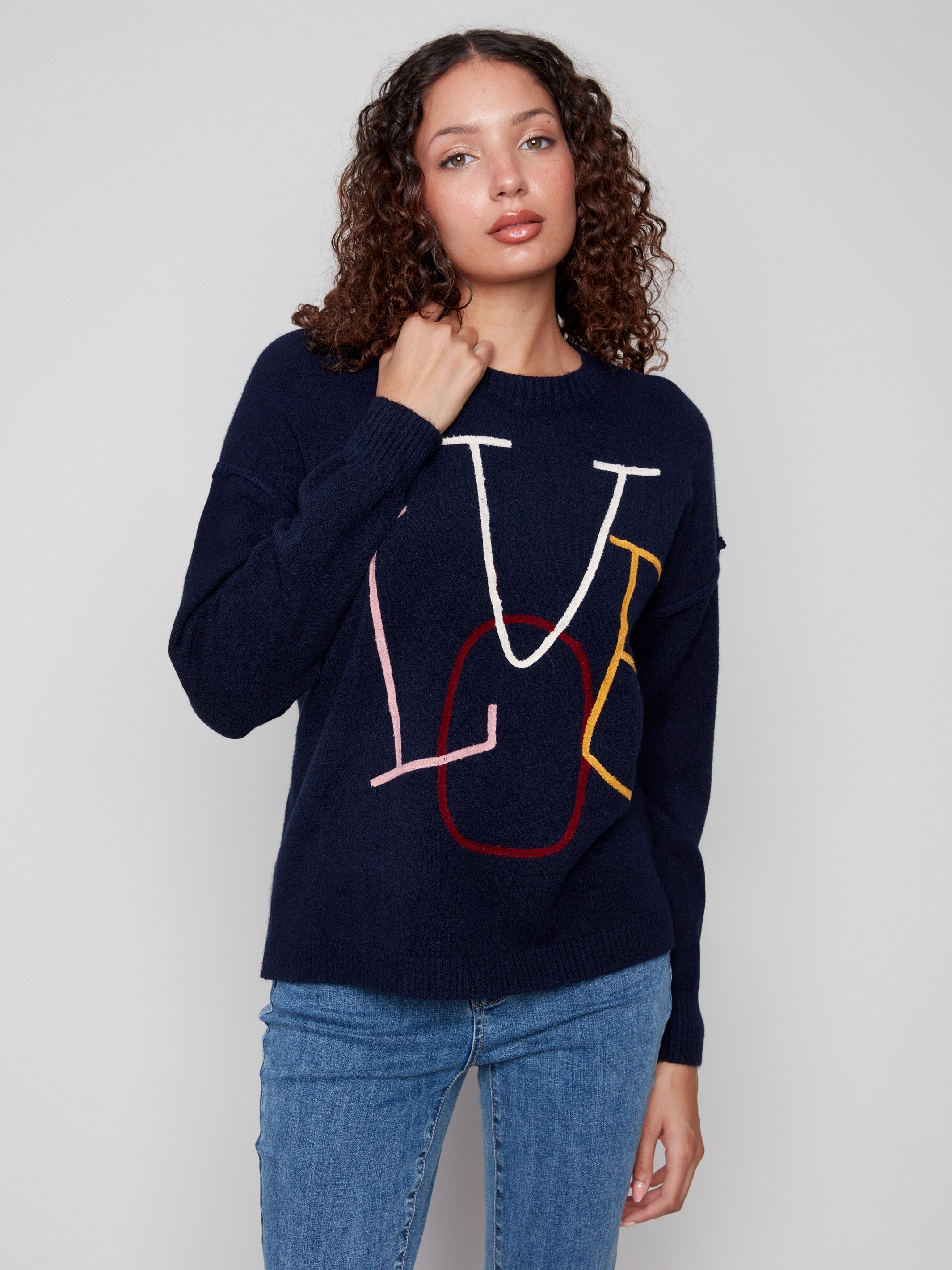 Embrace the casual elegance of this navy sweater with ribbed detailing and colorful embroidered text by Charlie B.