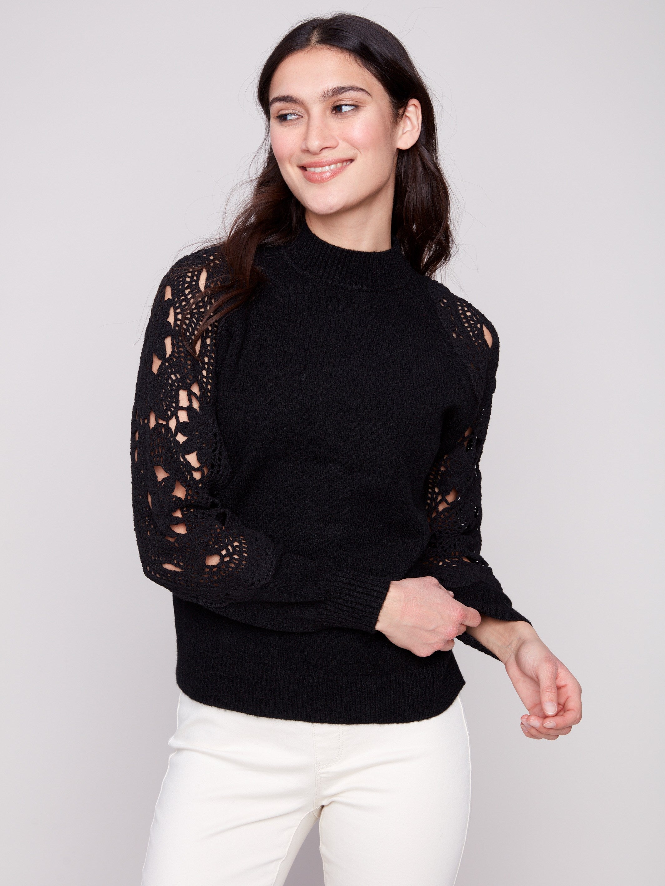 Chic black sweater showcasing intricate crochet sleeves and ribbed cuffs, perfect for any stylish outfit by Charlie B.