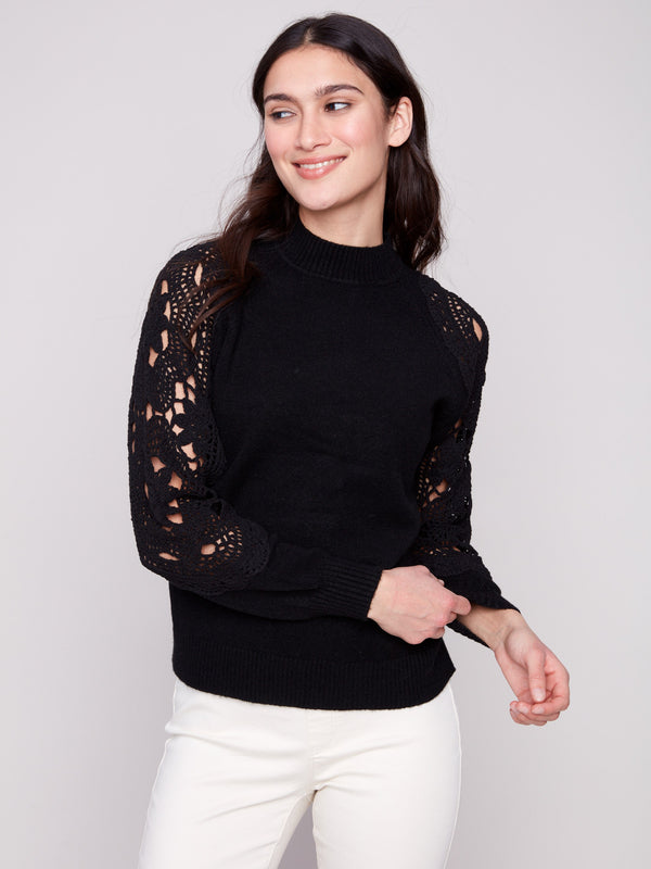 Chic black sweater showcasing intricate crochet sleeves and ribbed cuffs, perfect for any stylish outfit by Charlie B.