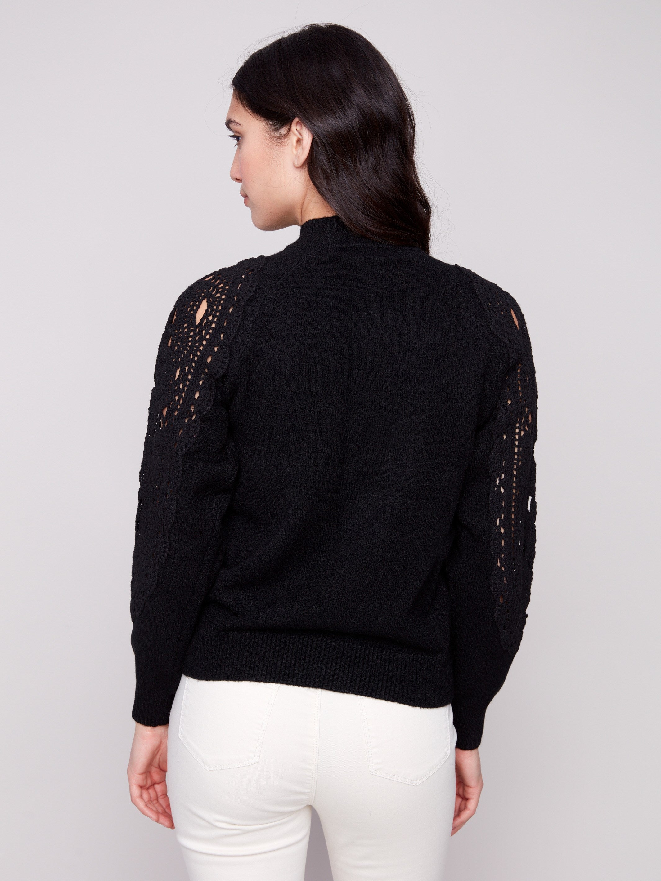 Sophisticated black mock neck sweater adorned with detailed crochet patterns on the sleeves for added flair by Charlie B.