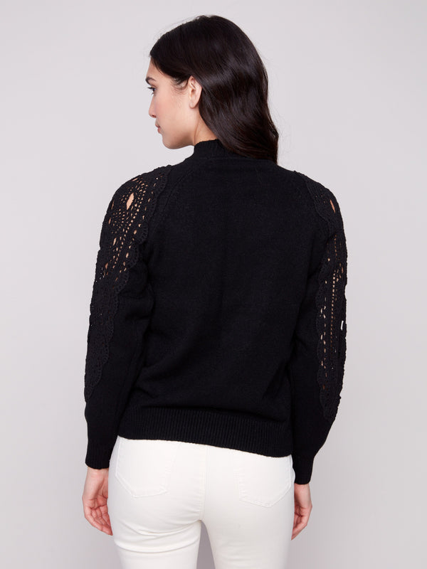 Sophisticated black mock neck sweater adorned with detailed crochet patterns on the sleeves for added flair by Charlie B.