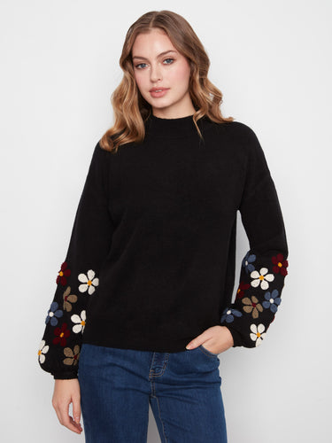 Black sweater featuring long balloon sleeves with colorful floral embroidery by Charlie B.