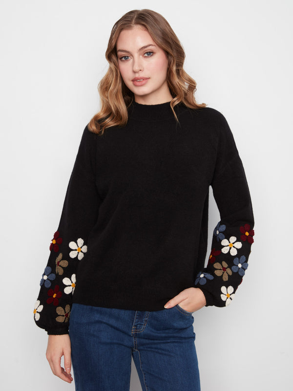 Black sweater featuring long balloon sleeves with colorful floral embroidery by Charlie B.