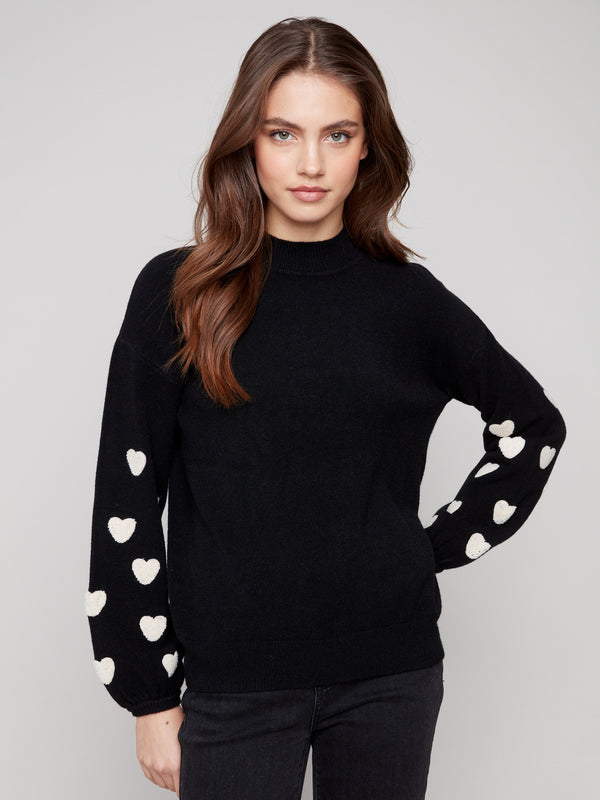 Chic black sweater with a mock neck and charming white hearts, showcasing a stylish drop shoulder design by Charlie B.