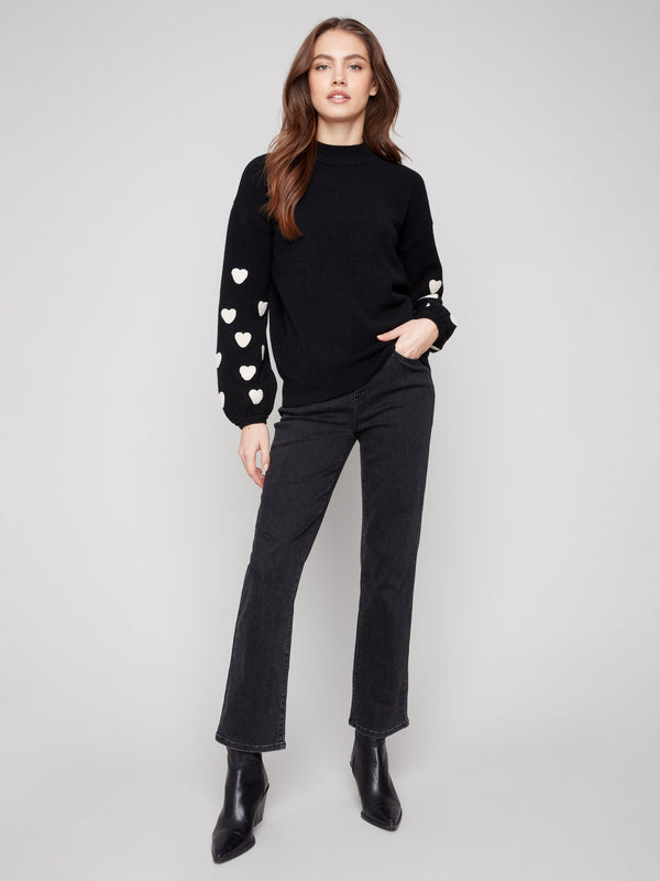 Elegant black sweater adorned with boucle heart embroidery on the sleeves, featuring a cozy mock neck by Charlie B.