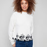 Ecru sweater featuring a mock neck and intricate black floral lace hem, showcasing a drop shoulder design by Charlie B.