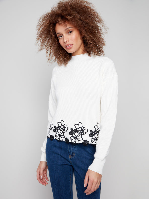 Stylish ecru mock neck sweater adorned with drop shoulder design and beautiful floral lace accents by Charlie B.