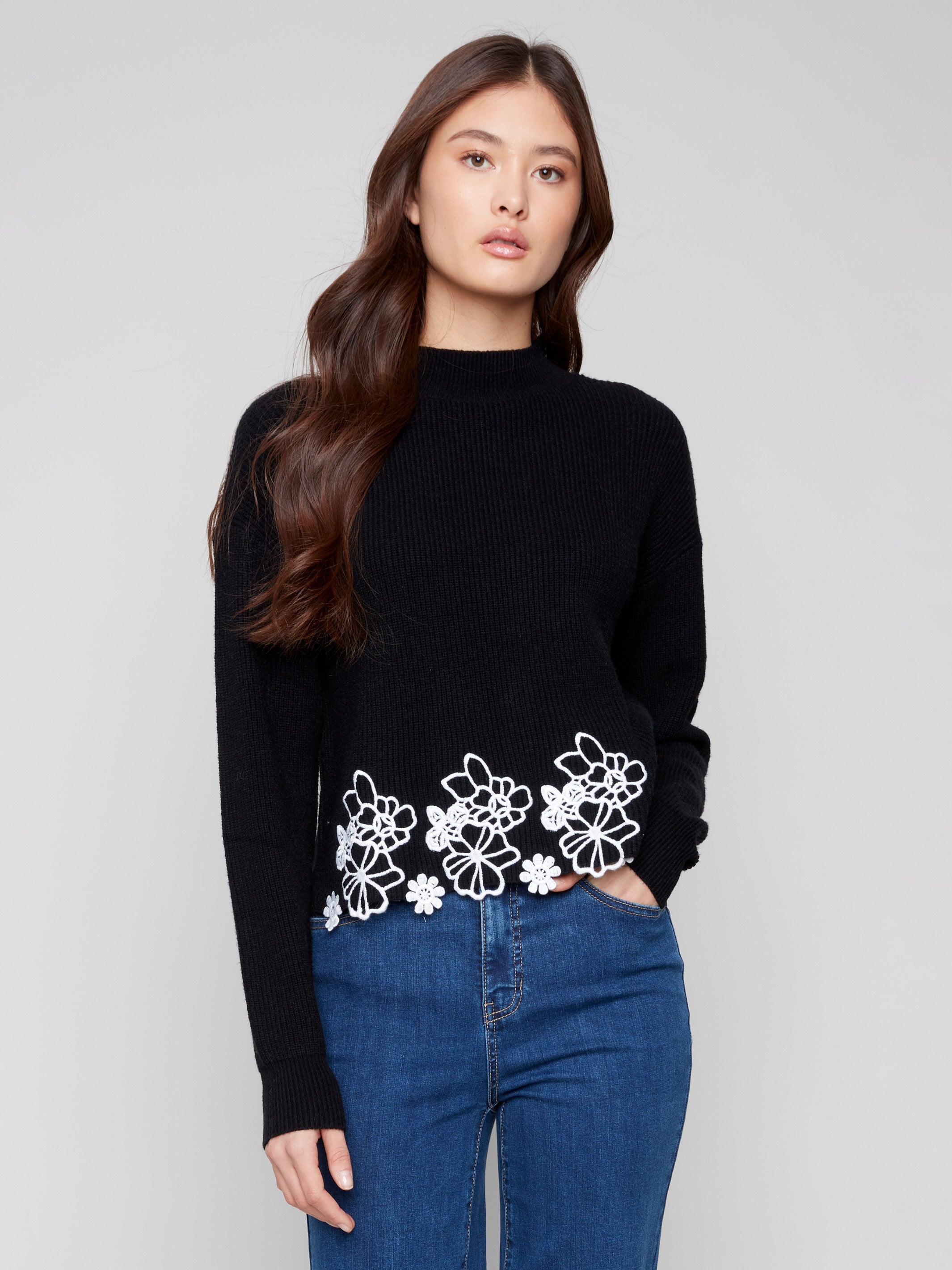 Black sweater featuring a chic drop shoulder design and white floral lace hem, perfect for stylish comfort by Charlie B.