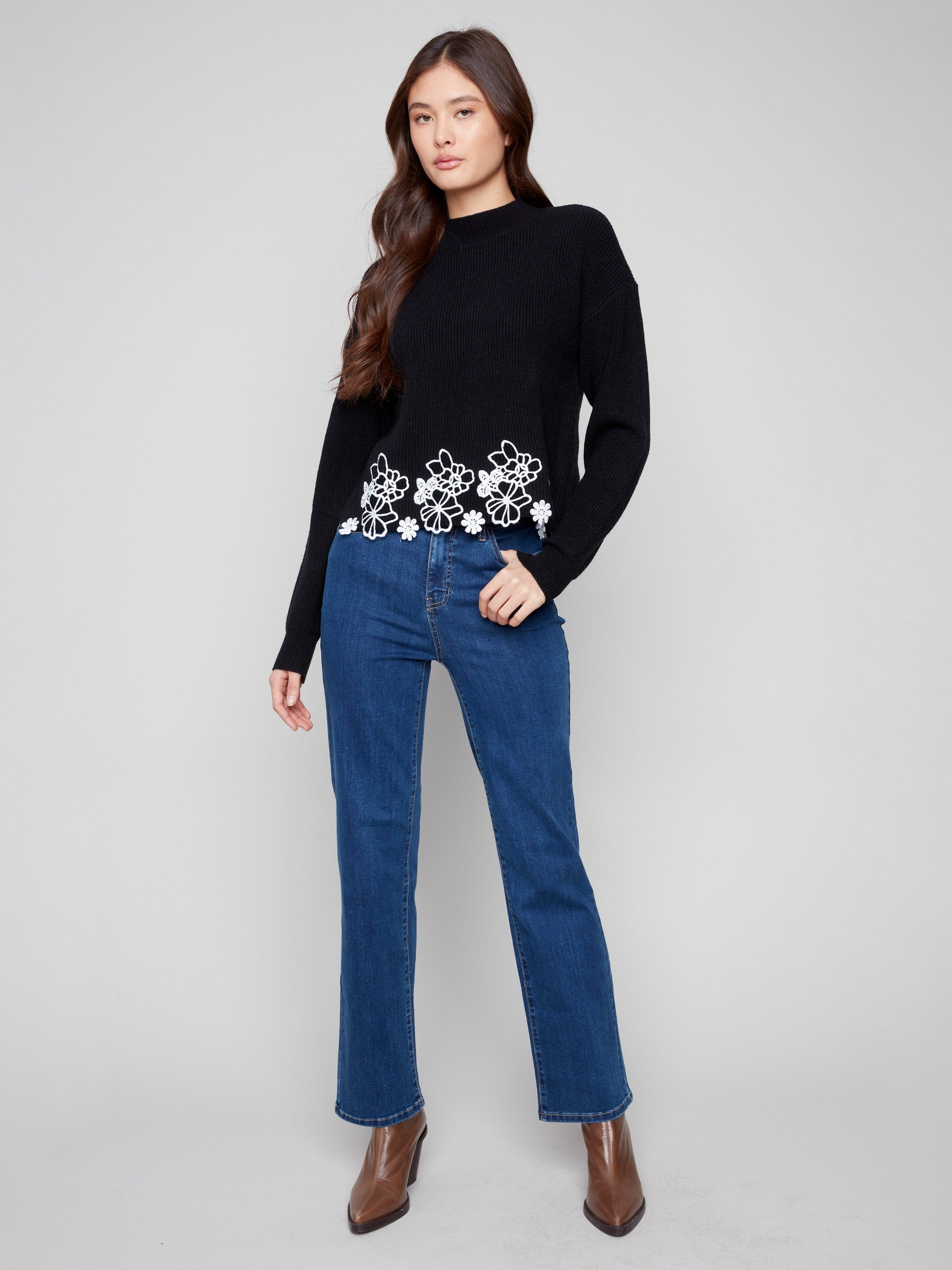 Charming black sweater with hip-length cut and delicate white floral lace detail, offering versatile elegance by Charlie B.