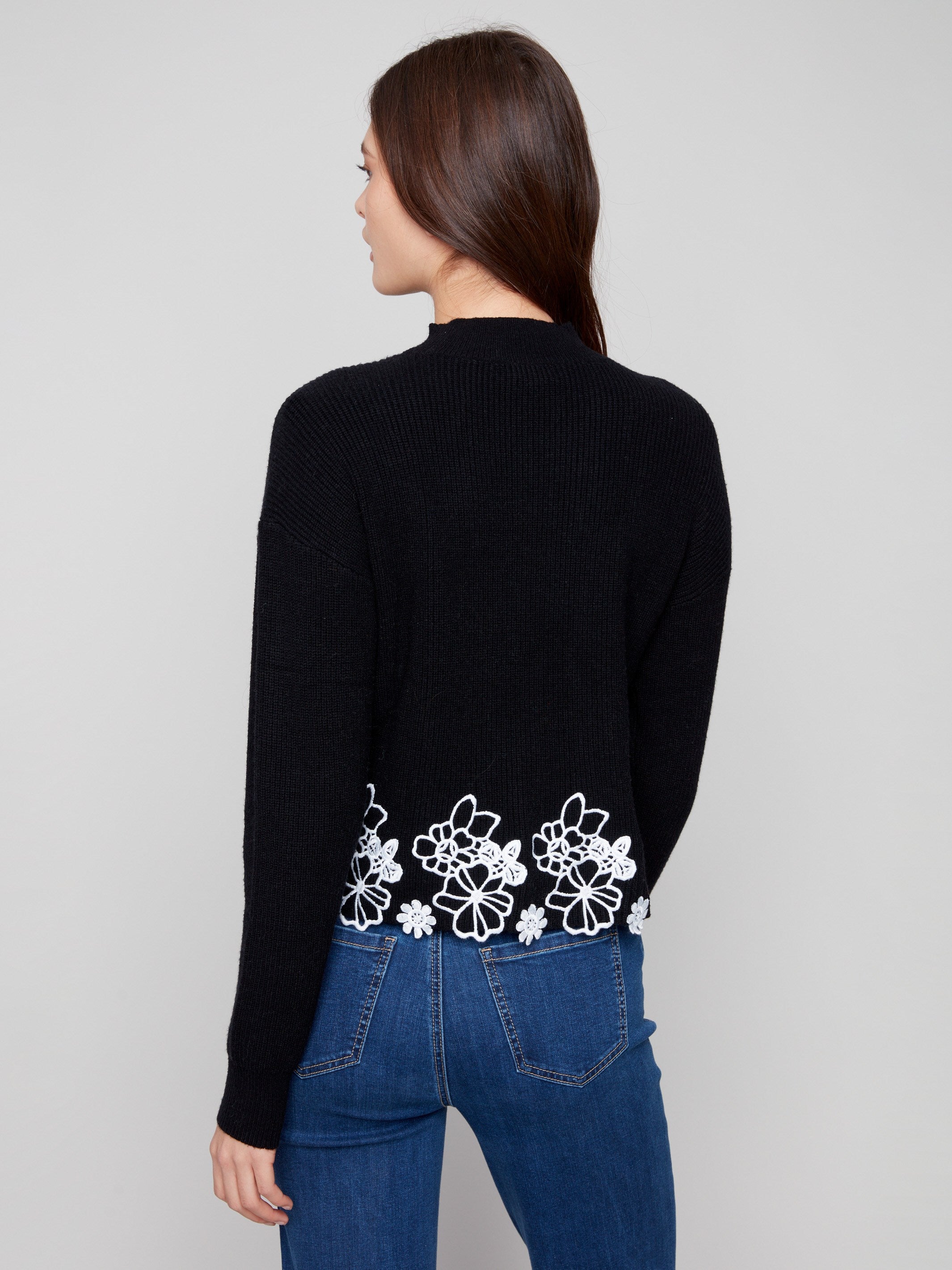 Stylish black mock neck sweater showcasing intricate floral lace hem and cozy drop shoulder fit by Charlie B.