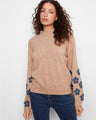 Sweater with a cozy mock neck design, enhanced by floral patches along the sleeves for a charming touch. By Charlie B.