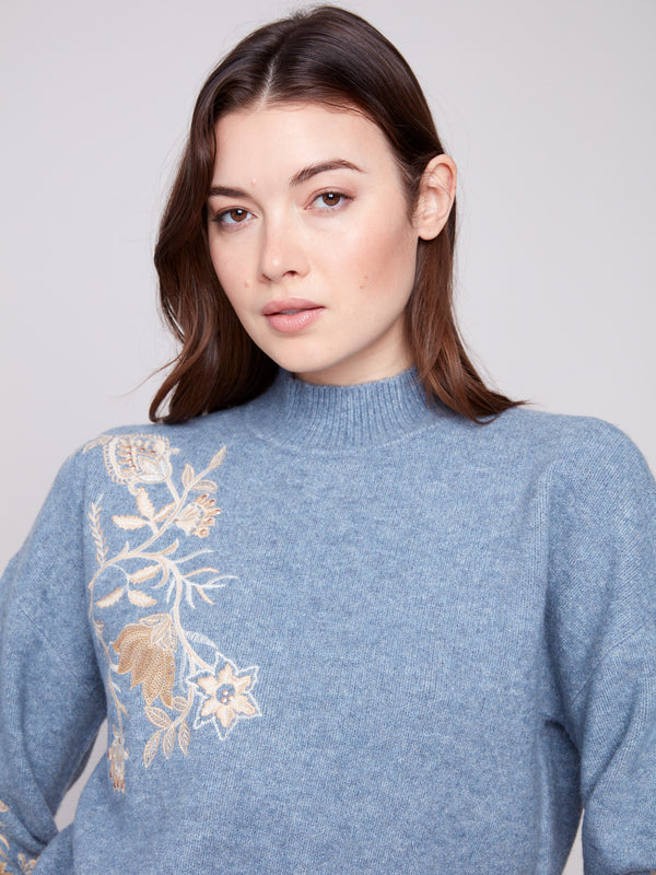 Denim knitwear featuring elegant floral designs with sequin highlights, complemented by drop shoulders by Charlie B.