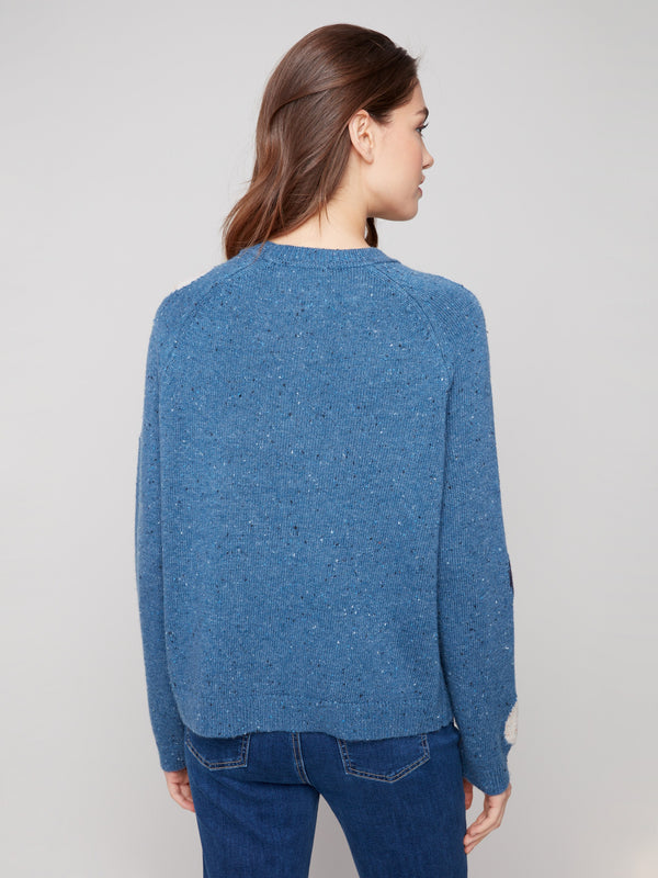 Polished look achieved with the elegant mock neck and vibrant polka dots on this blue sweater by Charlie B.