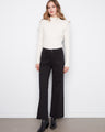 Black wide-leg twill pants with stretch fabric, paired with black boots and a white sweater by Charlie B.