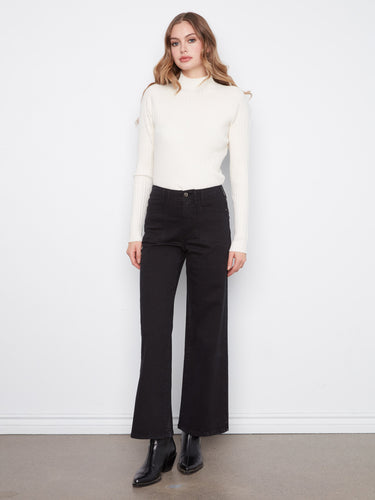 Black wide-leg twill pants with stretch fabric, paired with black boots and a white sweater by Charlie B.
