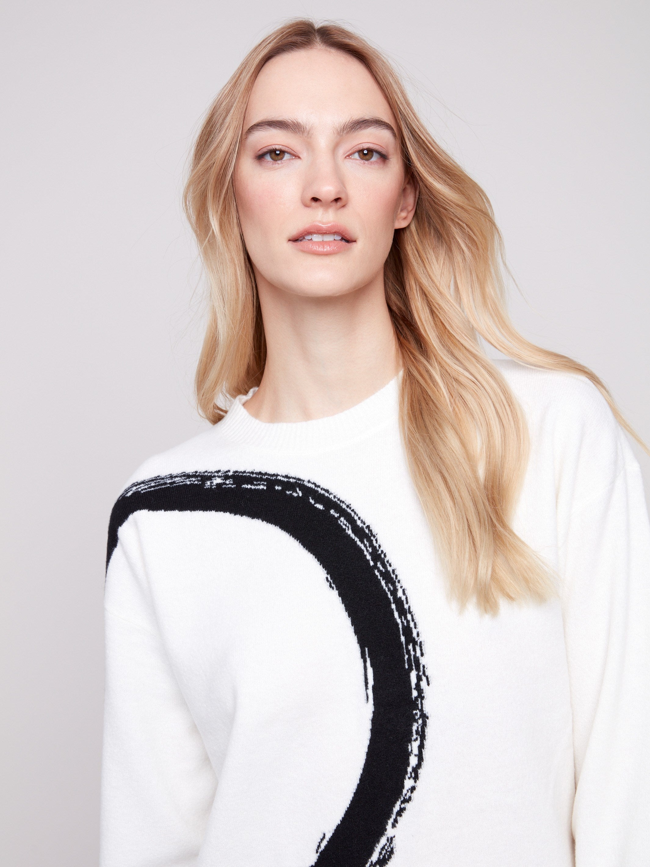 Long sleeve ecru sweater adorned with a bold black abstract circle design, offering comfort and style by Charlie B.